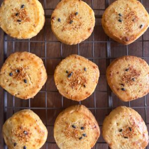 9 circular shichimi togarashi spice cookies (3 across, 3 down) on a cooling rack. The cookies have a red shichimi spice sprinkled on top with black and white sesame seeds.